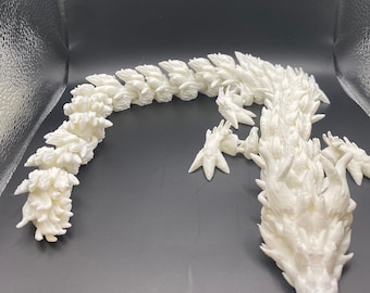 Könnte beinhalten: Weiße 3D-gedruckte Drachenskulptur mit einem langen, segmentierten Körper und einem detaillierten Kopf mit scharfen Zähnen und Stacheln.