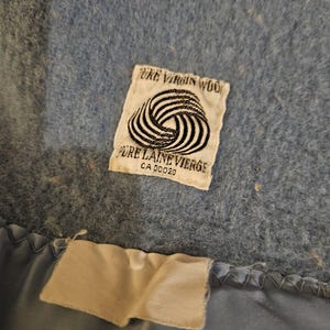 May include: A blue wool blanket with a white label that reads "Pure Virgin Wool" and "Pure Laine Vierge" with a CA number.