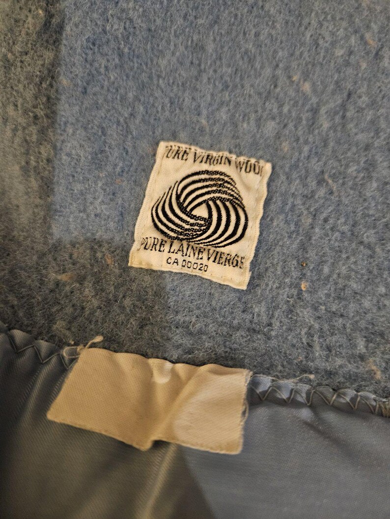 May include: A blue wool blanket with a white label that reads "Pure Virgin Wool" and "Pure Laine Vierge" with a CA number.