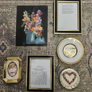 May include: A collection of decorative items including framed art and text. Features a floral painting, framed pages, a plate with a swan design, and a heart-shaped coaster with floral details. The frames are gold and black.