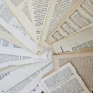 May include: A collection of vintage off-white paper pages from books and sheet music arranged in a fan shape. The pages feature various black printed text, musical notation, and numbered sections with visible torn edges and aged, yellowed textures.