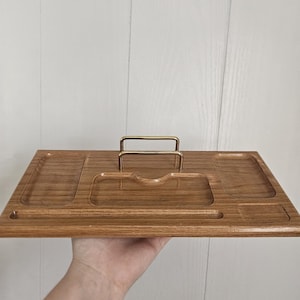 Peut inclure: Un plateau organisateur de bureau rectangulaire en bois avec une finition à grain naturel. Le plateau comprend plusieurs compartiments encastrés de tailles variées et un support central en fil métallique doré.