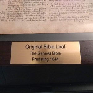 Puede incluir: Una placa dorada con texto negro que dice "Original Bible Leaf, The Geneva Bible, Predating 1644".