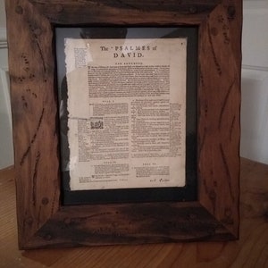 Puede incluir: Una impresi&oacute;n enmarcada de una vieja p&aacute;gina de libro con el t&iacute;tulo "The PSALMES of DAVID." La p&aacute;gina est&aacute; en blanco y negro y tiene un marco de madera marr&oacute;n con detalles met&aacute;licos.