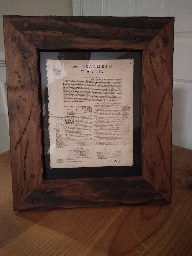 Puede incluir: Una impresi&oacute;n enmarcada de una vieja p&aacute;gina de libro con el t&iacute;tulo "The PSALMES of DAVID." La p&aacute;gina est&aacute; en blanco y negro y tiene un marco de madera marr&oacute;n con detalles met&aacute;licos.