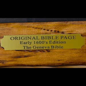 Puede incluir: Una placa dorada con texto negro dice "ORIGINAL BIBLE PAGE Early 1600's Edition The Geneva Bible".