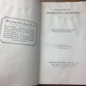 May include: Open book with the title "Practical Descriptive Geometry" by William Griswold Smith. The book is a second edition published by McGraw-Hill Book Company, Inc. in 1916. The left page features a list of publications.