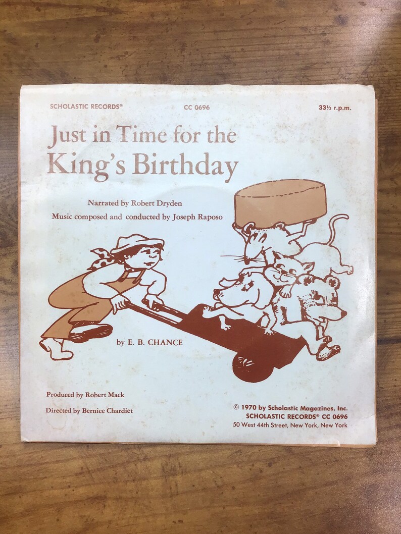 Peut inclure: Une pochette d'album vintage avec une illustration de dessin anim&eacute; d'un gar&ccedil;on poussant une brouette pleine d'animaux. L'album est intitul&eacute; "Just in Time for the King's Birthday" par E. B. Chance. L'album est une sortie de Scholastic Records.