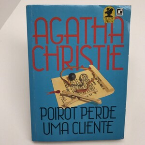 May include: A blue book cover with the title "AGATHA CHRISTIE" in red letters. The book title is "POirot PERDE UMA CLIENTE". The cover features a skull and crossbones, a magnifying glass, and a rolled up piece of paper.
