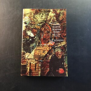 May include: A hardcover book titled "Lions, Harts, Leaping Does and Other Stories" by J.F. Powers. The cover features an abstract painting in shades of brown, gold, and red, with visible text. The book is rectangular and appears to be in good condition.