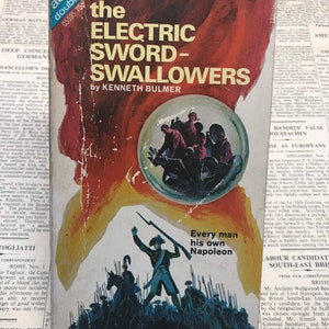 May include: A vintage paperback book cover with a red background and a scene of soldiers marching. The title is "The Electric Sword-Swallowers" by Kenneth Bulmer. The text "Every man his own Napoleon" is also on the cover.