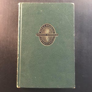 May include: A vintage green hardcover book with gold lettering and a gold emblem that reads "Funk & Wagnalls Standard Reference Encyclopedia". The book has a slightly worn appearance, suggesting age and use. The cover is a solid, muted green.