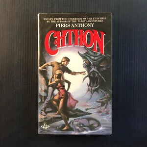 May include: A paperback book titled "Chthon" by Piers Anthony. The cover art depicts a man and woman fleeing a monstrous creature. The title is in large red letters. The book is part of the Berkley Science Fiction series.