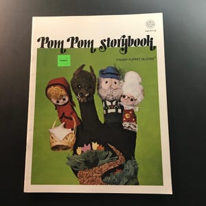 May include: A vintage "Pom Pom Storybook" with finger puppet gloves. The cover features a green background with a black hand puppet design. The puppets include Little Red Riding Hood, a wolf, an old man, and an elderly woman.
