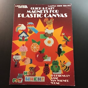 May include: A vintage craft book cover titled "Quick & Easy Magnets for Plastic Canvas." The cover features various cross-stitch designs of animals, food, and objects. The color scheme is primarily red, orange, and yellow.