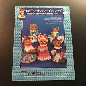 May include: A blue and white cover for crochet air fresheners. The cover features five charming little bear designs, each wearing a different outfit. The cover also includes the text "Air Freshener Covers" and "Crochet Decorative Series Set 3".