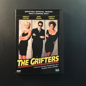May include: DVD case for "The Grifters" movie. The cover features Anjelica Huston, John Cusack, and Annette Bening. The title is in large yellow letters, with the tagline "Seduction. Betrayal. Murder. Who's Conning Who?"