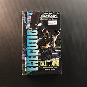 May include: A paperback book titled "The Executioner: Call to Arms" by Don Pendleton. The cover features a man holding a rifle, an eagle, and the text "America is under siege within its borders."