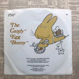May include: Vintage vinyl record cover for "The Candy Egg Bunny." The cover features a cartoon bunny holding a basket of Easter eggs, with a smaller bunny and text on a newsprint background.