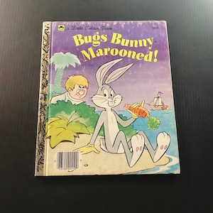 May include: A vintage Little Golden Book titled "Bugs Bunny Marooned!" features Bugs Bunny holding a carrot on a beach scene. The cover has a purple and yellow background with a cartoon illustration of Bugs Bunny and a boy.