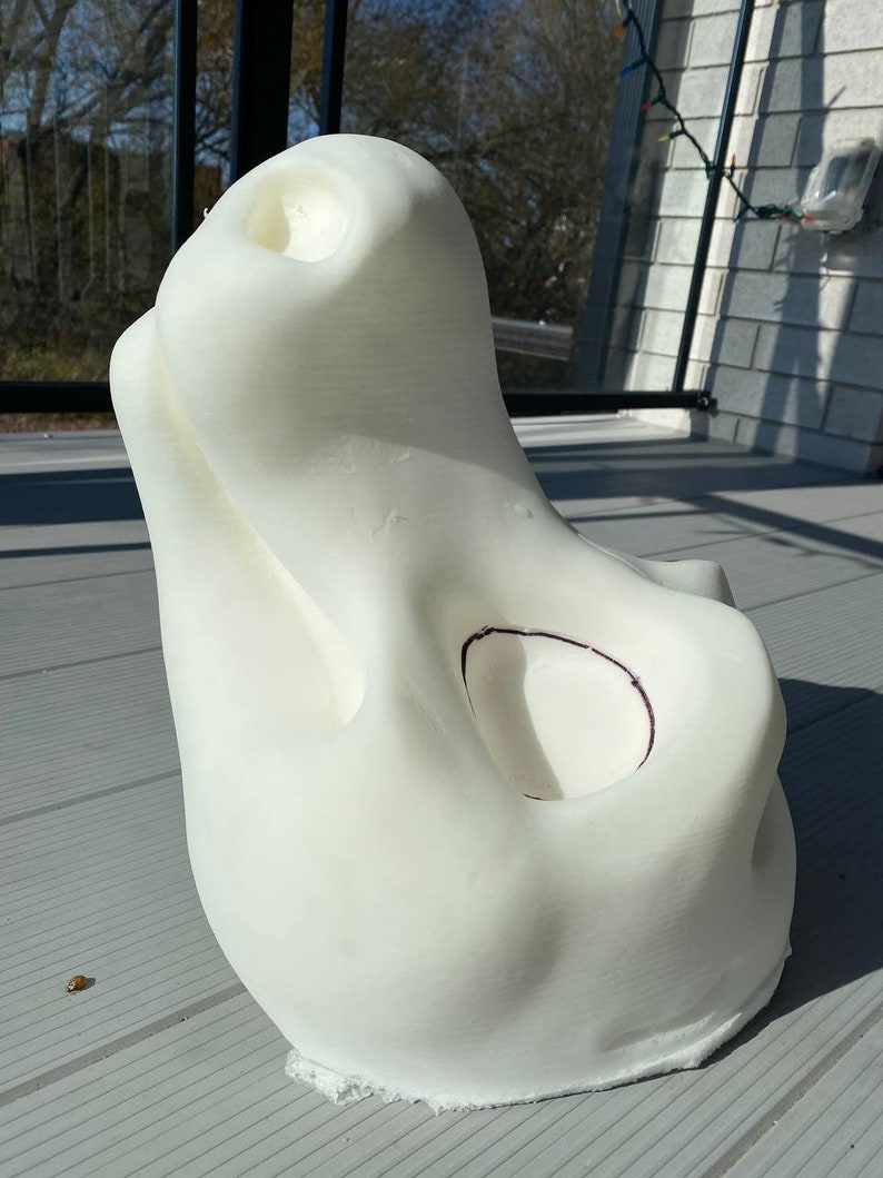 Pu&ograve; includere: Scultura bianca stampata in 3D con una forma organica liscia. La scultura ha una grande apertura nella parte superiore e una apertura pi&ugrave; piccola sul lato. La scultura &egrave; appoggiata su una superficie grigia.