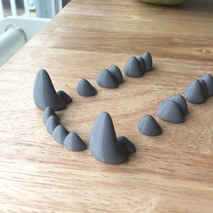 May include: A set of grey 3D printed teeth, arranged in a mouth shape on a wooden surface.