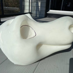Pu&ograve; includere: Testa di fursuit bianca in schiuma, non finita, con una grande bocca aperta e un piccolo naso rotondo. La testa &egrave; incompleta e ha una linea nera disegnata attorno all'area degli occhi.