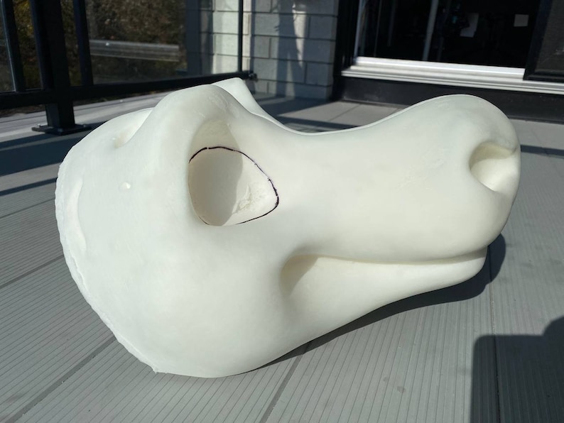 Pu&ograve; includere: Testa di fursuit bianca in schiuma, non finita, con una grande bocca aperta e un piccolo naso rotondo. La testa &egrave; incompleta e ha una linea nera disegnata attorno all'area degli occhi.