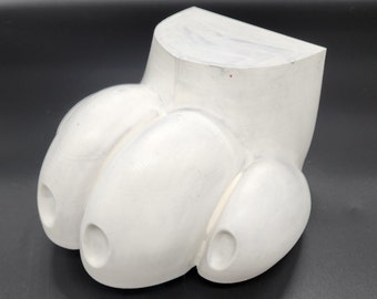 May include: White ceramic sculpture of a foot with three toes. The foot is smooth and rounded, with a slightly textured surface.