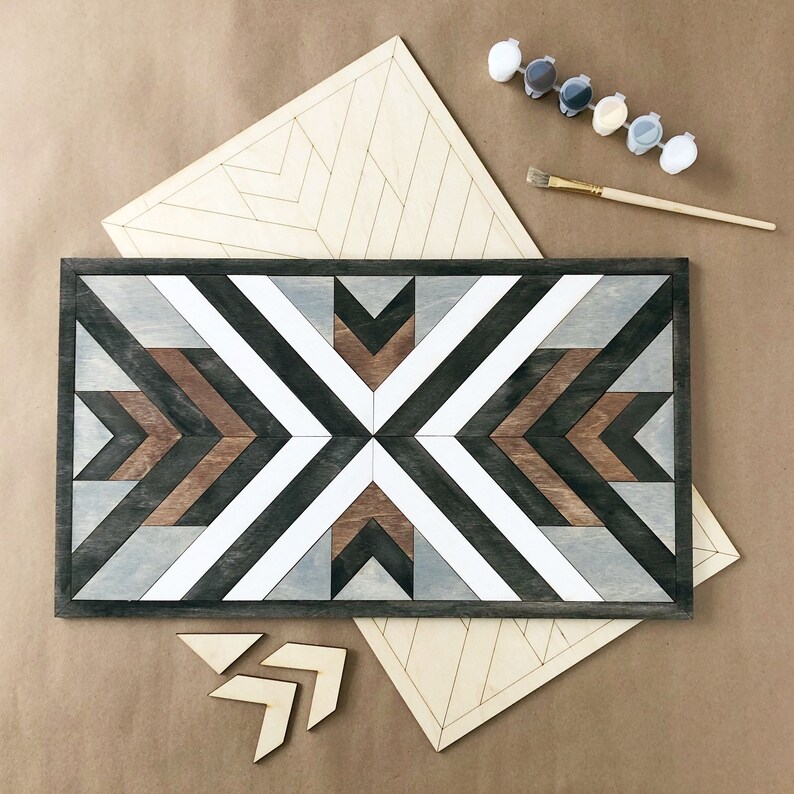 May include: A geometric wooden wall art piece with a black, white, brown, and grey colour scheme. The art is made up of multiple wooden pieces that are arranged in a geometric pattern. The art is unfinished and ready to be painted.