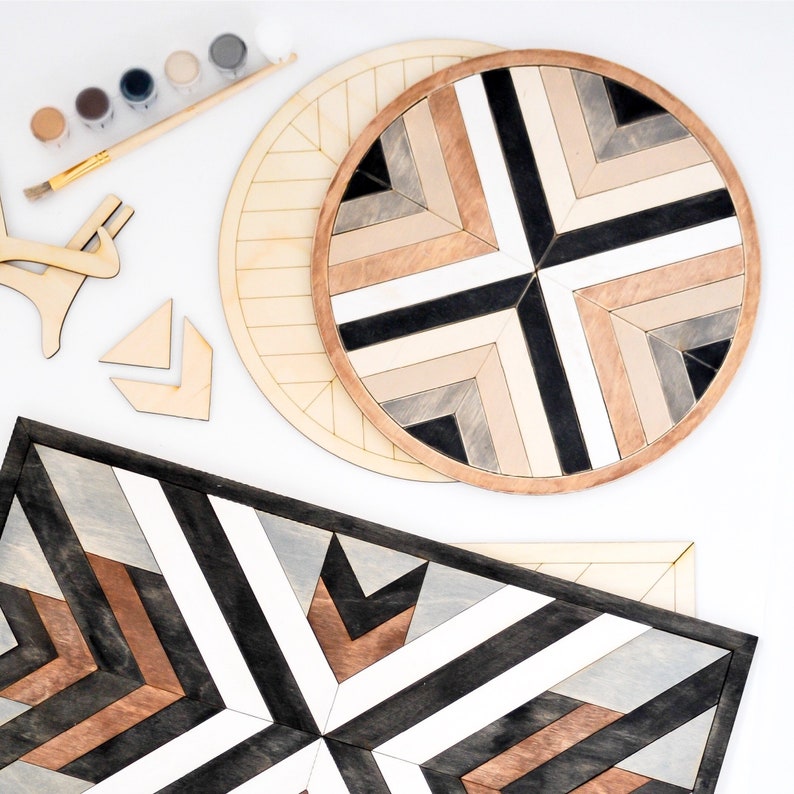 May include: Two wooden wall decor pieces with a geometric pattern of black, white and brown stripes. The larger piece is round and the smaller piece is rectangular.