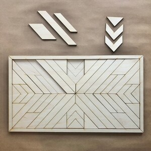 May include: A wooden geometric wall art piece with a white finish. The art is made up of multiple triangles and rectangles that create a pattern of intersecting lines. The art is framed in a thin, white frame.