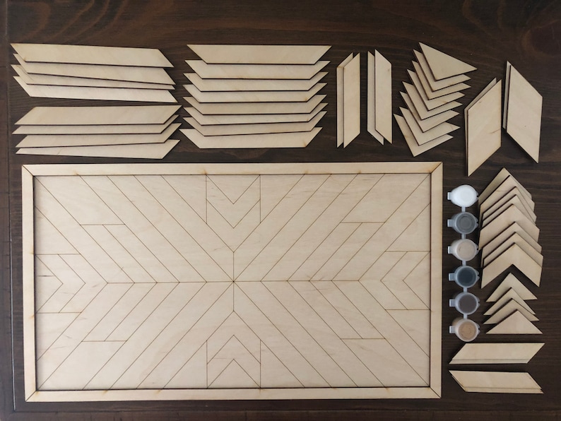 May include: A wooden geometric art kit with a variety of shapes and sizes of wood pieces. The kit includes a wooden frame, paint pots, and a paintbrush. The pieces are arranged in a pattern on a wooden surface.