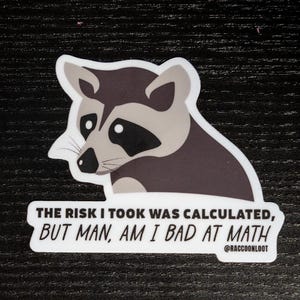 May include: A sticker featuring a cartoon raccoon with the text "THE RISK I TOOK WAS CALCULATED, BUT MAN, AM I BAD AT MATH" and the social media handle "@RACCOONLOOT".