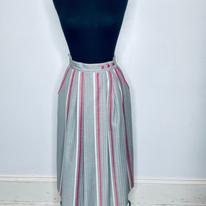 May include: A gray and white striped skirt with a red stripe running down the center of each white stripe. The skirt has a high waist and a pleated design.