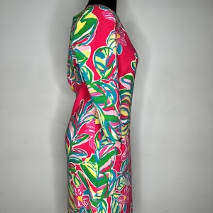 May include: A pink dress with a tropical print featuring green and blue leaves and pink flowers.