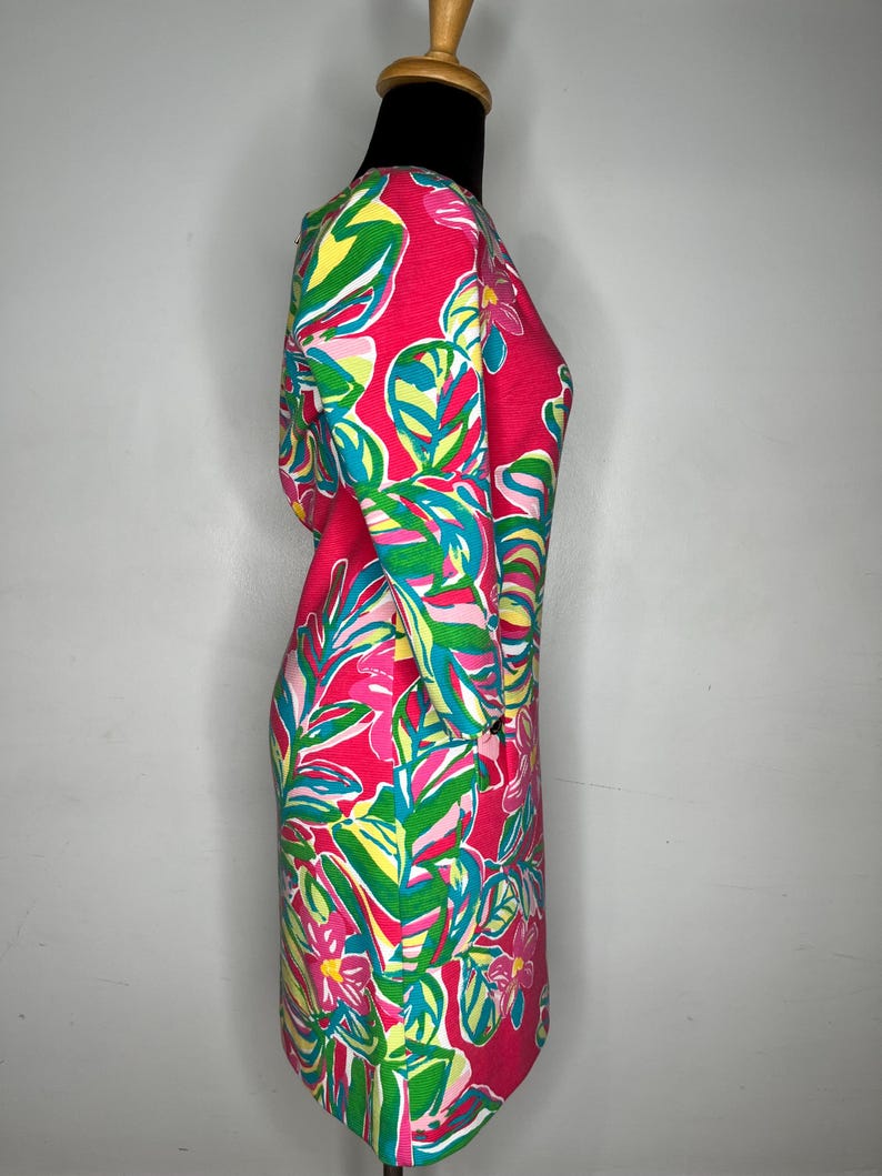 May include: A pink dress with a tropical print featuring green and blue leaves and pink flowers.