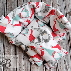 May include: Set of four white fabric corn bags with a gnome pattern in red, gray, and teal. The bags are arranged in a square shape with the largest bag in the center. The bags are labeled "Beebe's Corn Bags".