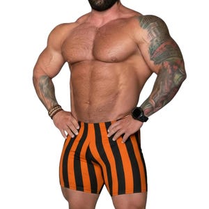 Puede incluir: Pantalones cortos deportivos ajustados con un llamativo patrón de rayas verticales en colores naranja y negro alternados. Los pantalones cortos tienen un dobladillo recto y un ajuste ceñido, diseñados para llegar al muslo con una cintura elástica.