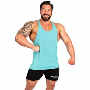 May include: A light turquoise racerback tank top with a scoop neckline and black athletic shorts featuring the white text "CAMP MUSCLE" printed on the lower left leg. The tank top has thin shoulder straps and a sleeveless design for mobility.