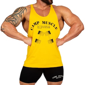 May include: A bright yellow sleeveless tank top featuring the black text CAMP MUSCLE BODYWEAR and a graphic of two crossed dumbbells. The tank top is paired with black athletic shorts that also display the text CAMP MUSCLE BODYWEAR in white.