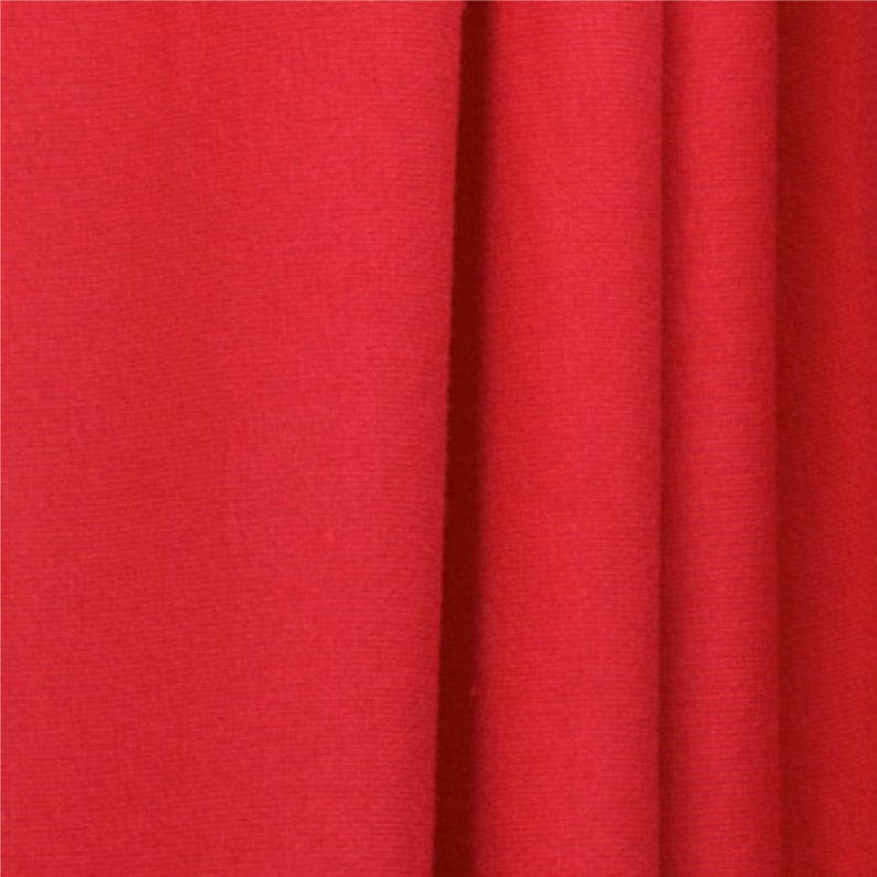 May include: Close-up of a smooth, red fabric with subtle folds and wrinkles. The fabric has a soft, even texture.