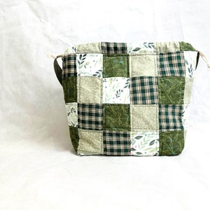 May include: A green and white patchwork drawstring bag with a floral and plaid pattern.
