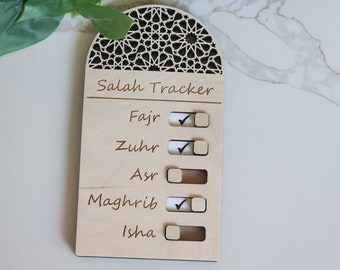 Puede incluir: Un rastreador de Salah de madera con un diseño de arco decorativo. El rastreador tiene cinco secciones para marcar las oraciones: Fajr, Zuhr, Asr, Maghrib e Isha. Cada sección tiene una casilla de verificación y un control deslizante.
