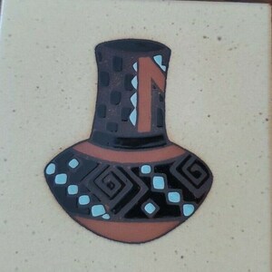 May include: A brown ceramic vase with a black and white geometric pattern and a blue and white design. The vase has a narrow neck and a wide base.