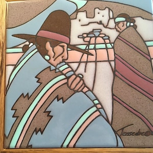 May include: A framed ceramic tile with a colorful illustration of two Native American figures wearing traditional clothing. The figures are standing in front of a building with a brown, pink, and blue background. The tile is signed "Tesseco" in the bottom right corner.
