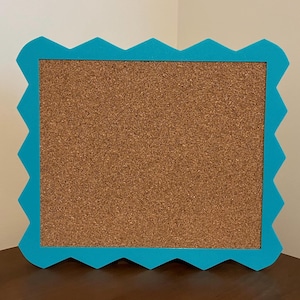 May include: A blue corkboard with a scalloped edge. The corkboard is blank and ready for use.