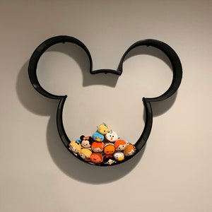 May include: Black Mickey Mouse-shaped wall shelf with a collection of colorful plush toys in the shape of Disney characters.