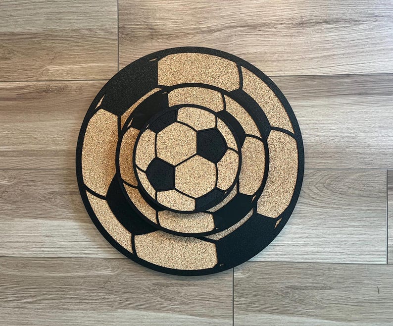 May include: Three cork coasters featuring a black and white football design. The coasters are stacked on top of each other.