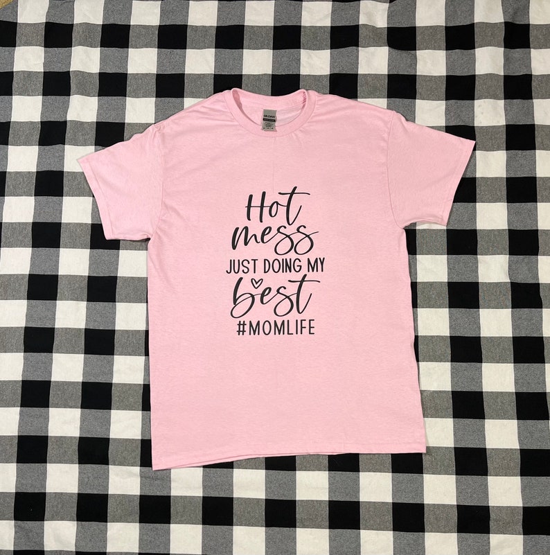 May include: Pink t-shirt with black text that reads "Hot mess just doing my best #momlife".